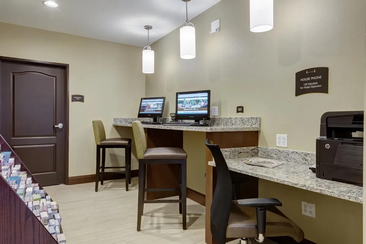 A convenient business center area featuring computers, bar stools at a granite countertop, and a printer, creating a functional space for guests to get work done or stay connected online.