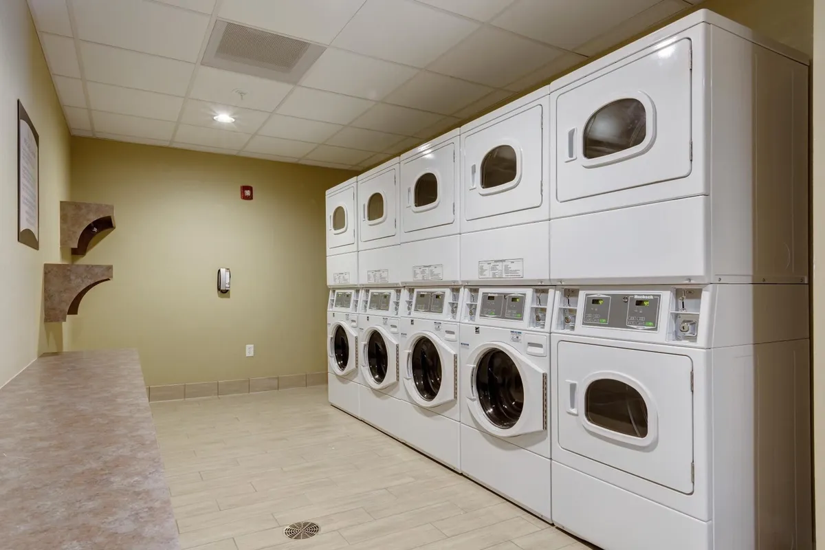 The photo displays a clean, efficient laundry area equipped with washing machines, dryers, and counter space for folding clothes. The environment is practical and inviting, enabling guests to conveniently handle laundry during longer stays.